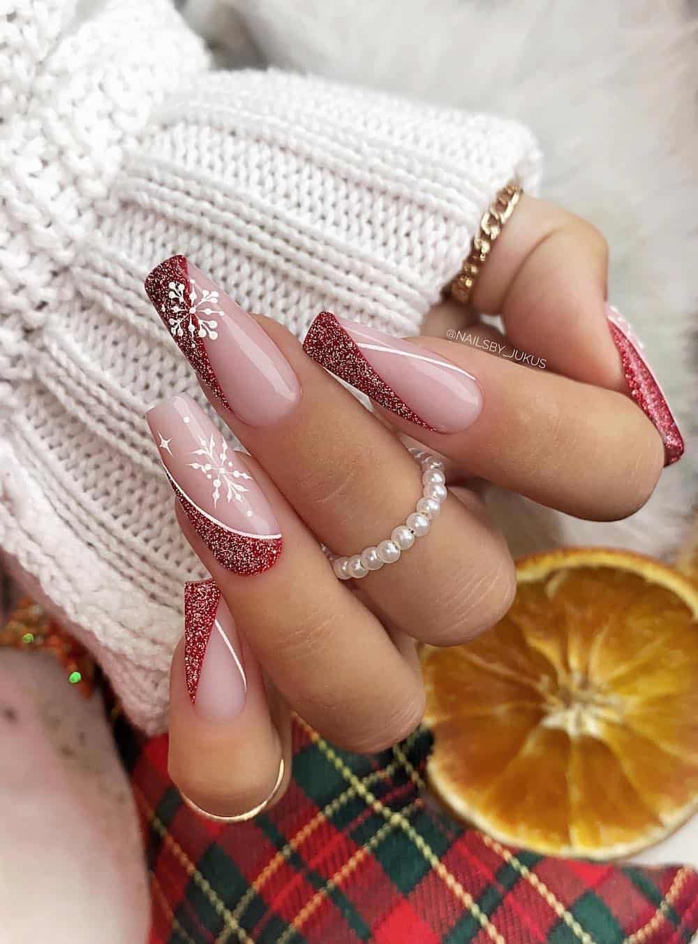 Modern red and white french tip manicure with silver glitter and white snowflake details.