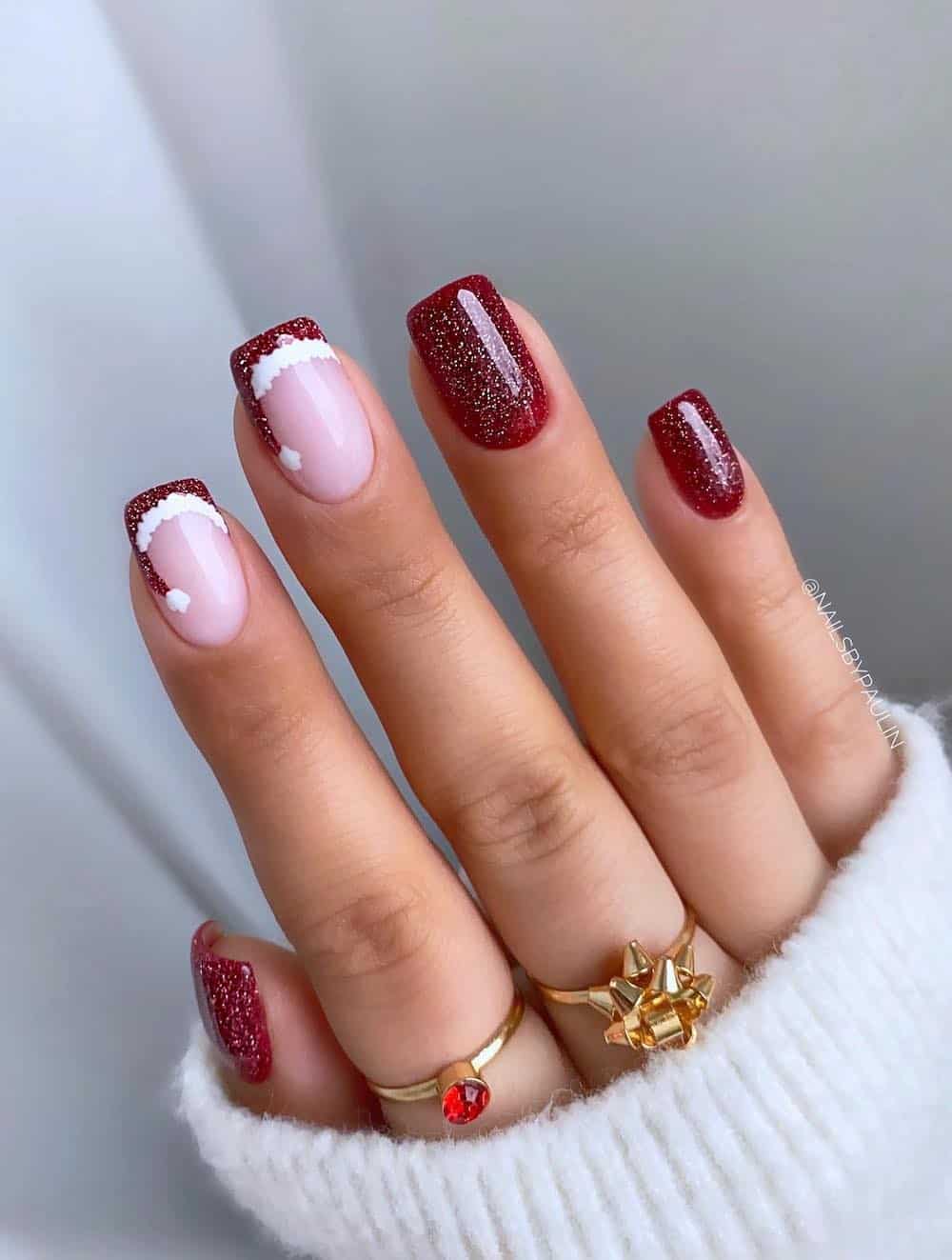 Red glitter manicure with Santa hat french tips.