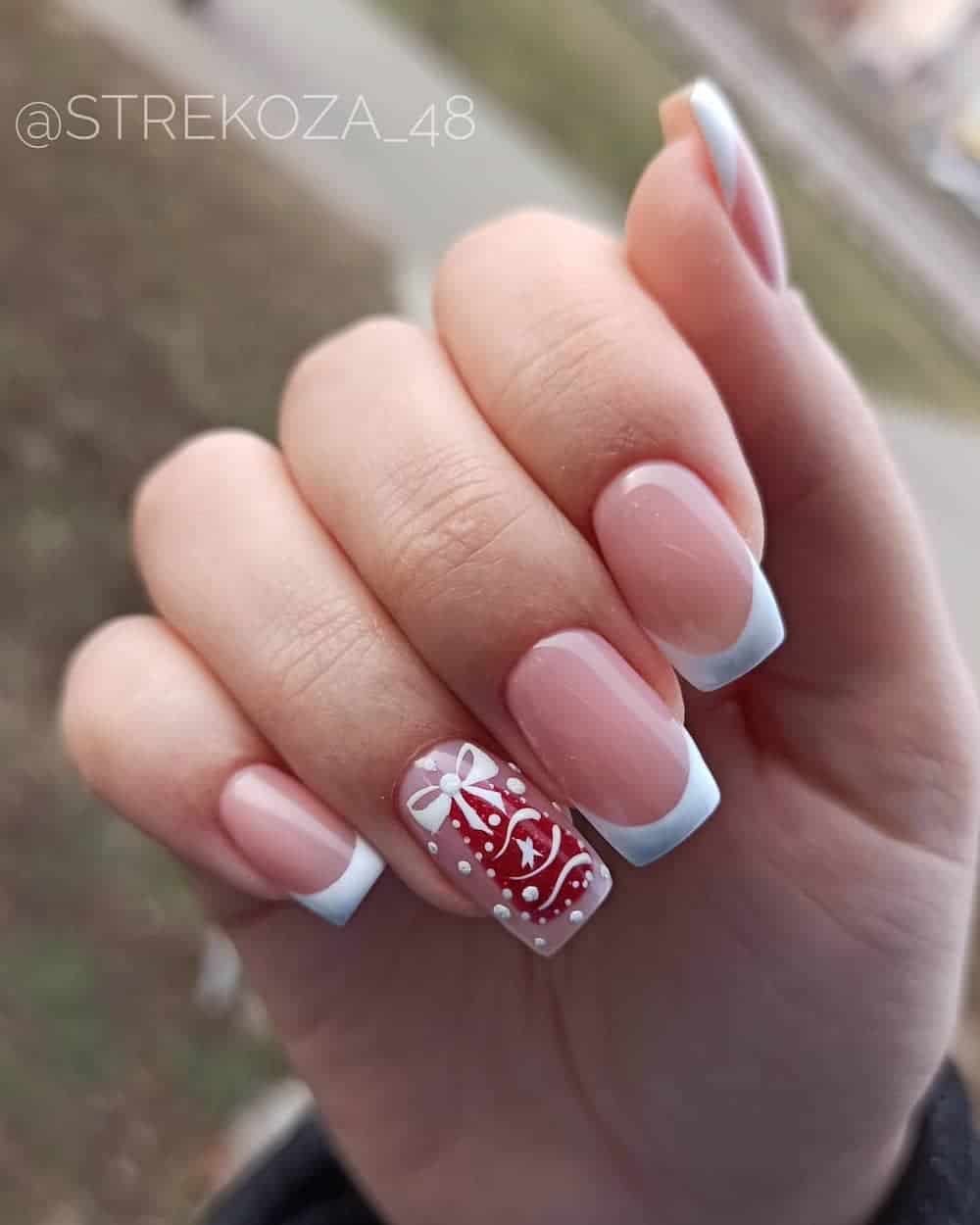 White french tip manicure with red Christmas ornament detail.