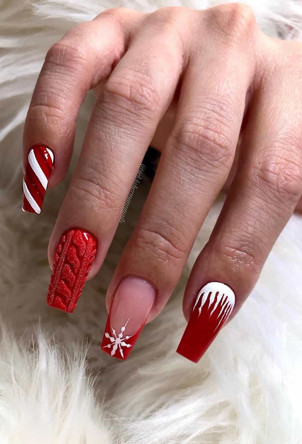 Bright red manicure with white snowflakes, candy cane details, sweater details and snow details.
