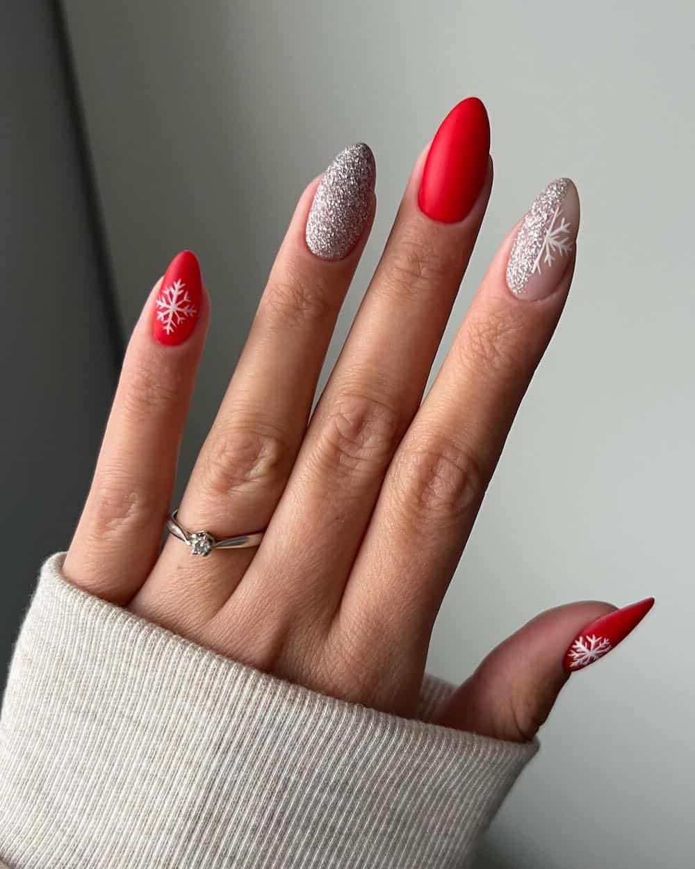 Red matte Christmas manicure with silver glitter and white snowflake details.