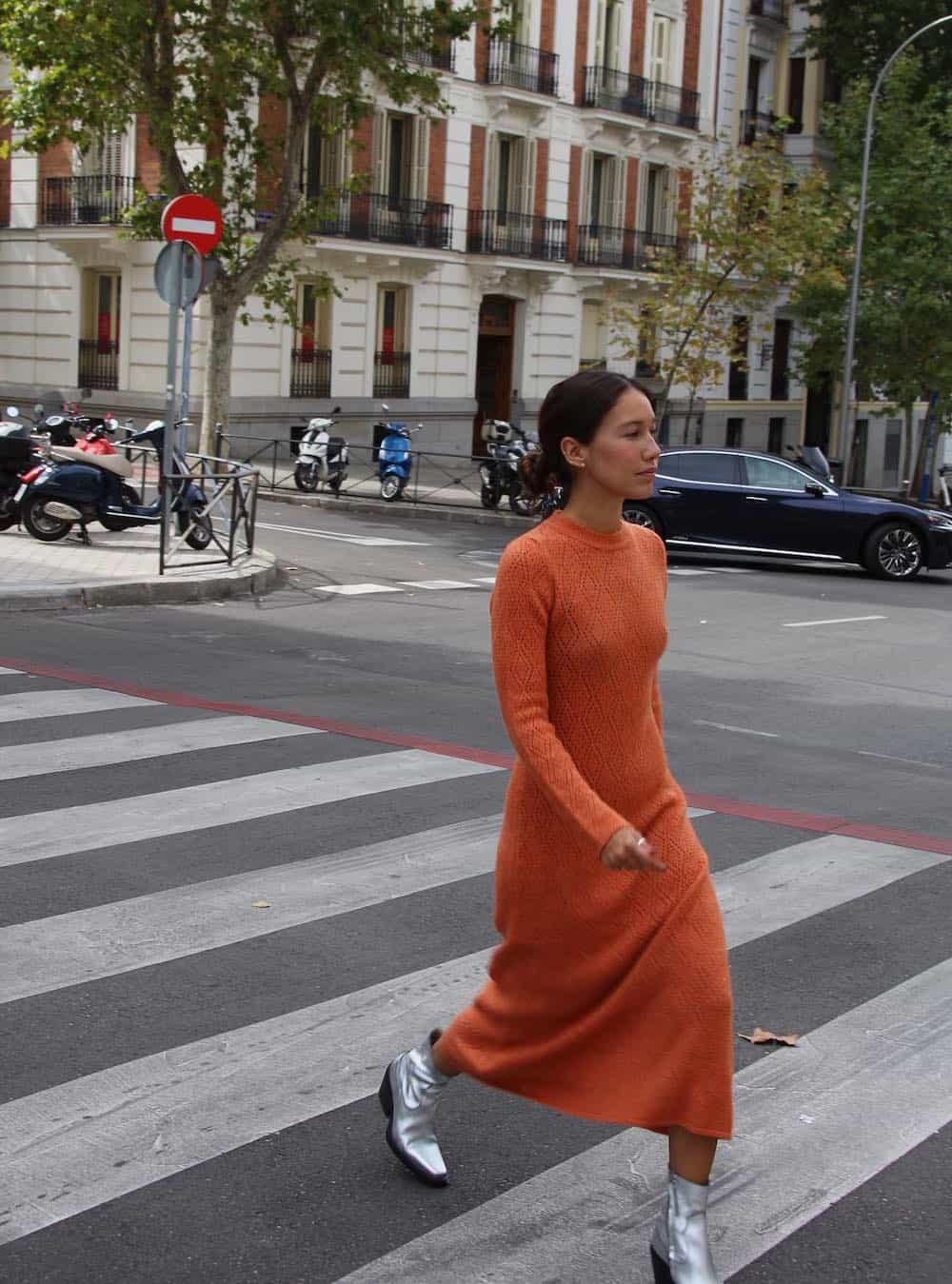 Woman wearing an orange sweater dress with silver booties.