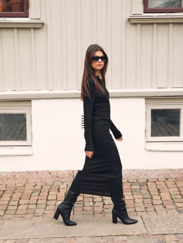 Woman wearing a black sweater dress with chunky black boots.