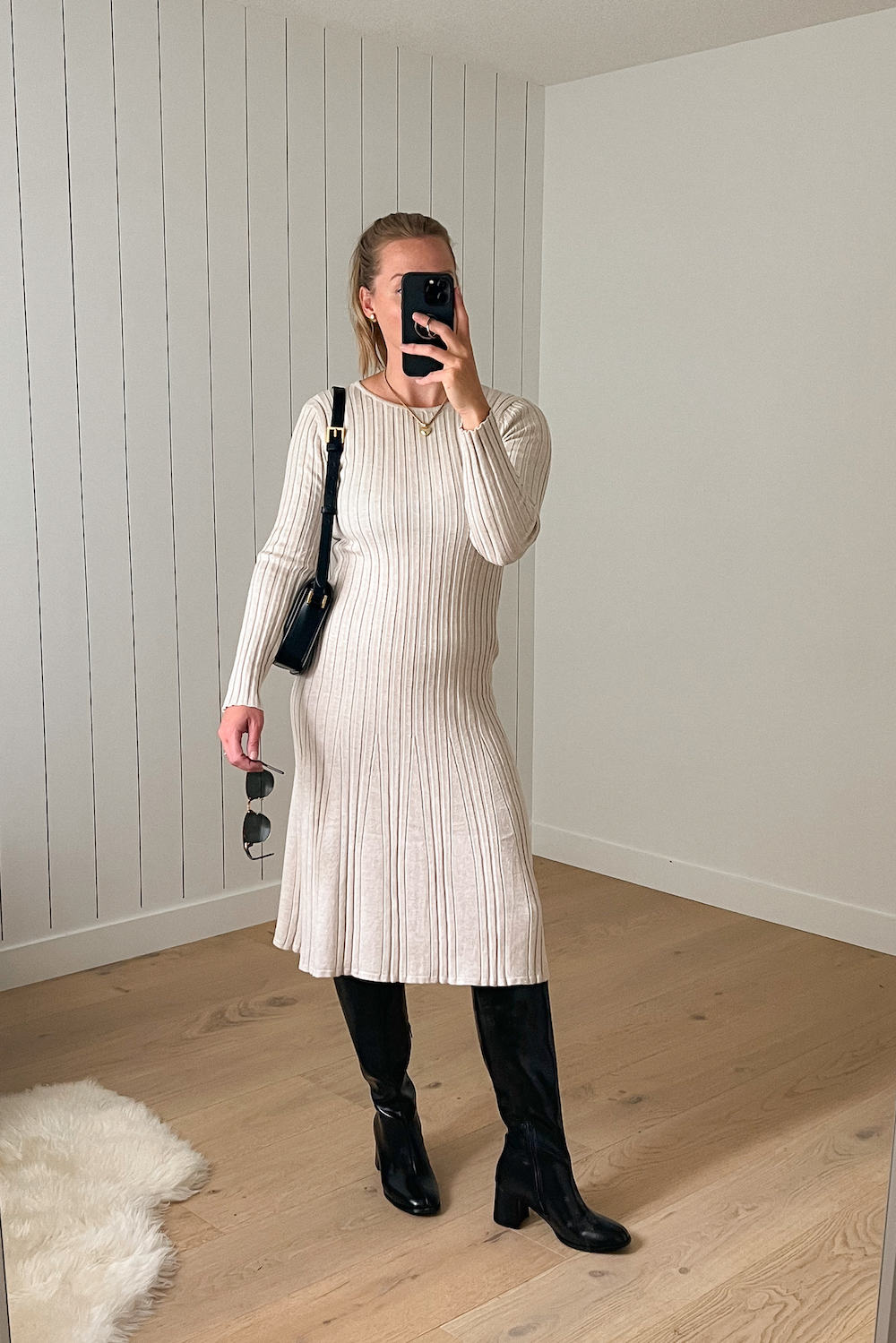 Woman wearing a cream sweater dress with tall black boots