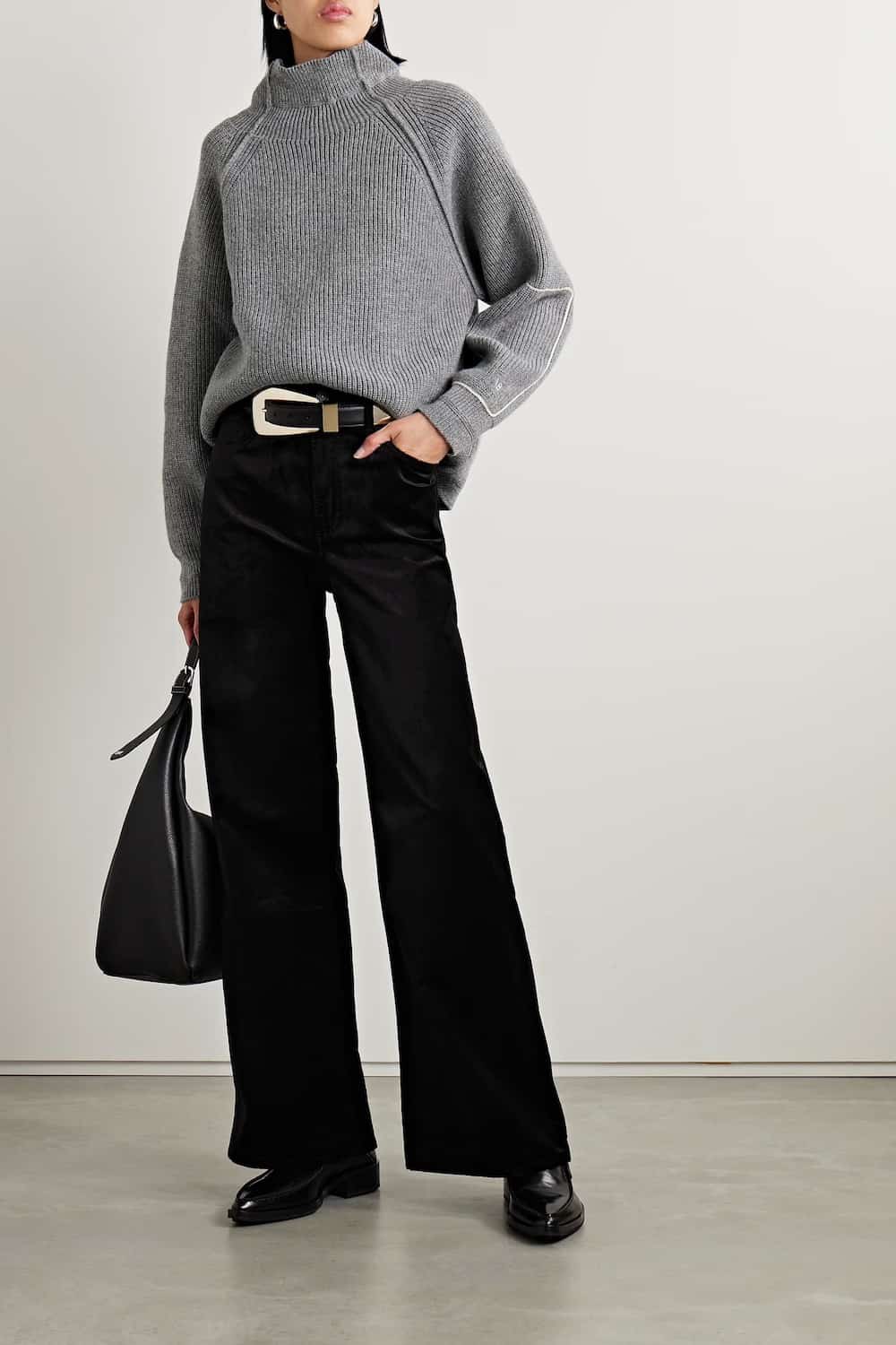 Woman wearing black velvet wide leg pants with a grey turtleneck sweater and loafers.