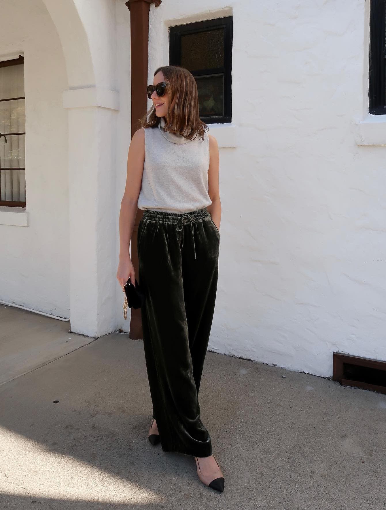 Woman wearing green velvet pants and Mary Jane flats with a tank top turtle neck sweater.