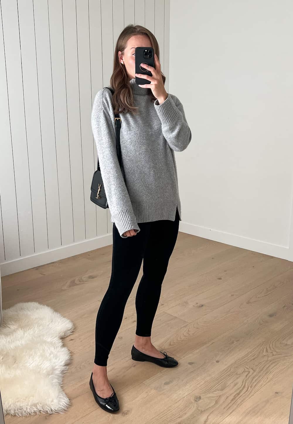 Woman wearing black velvet leggings with a grey sweater and ballet flats.