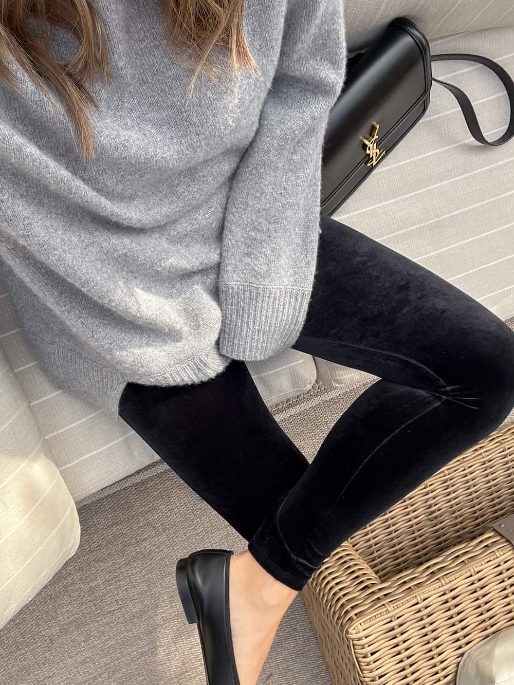 Up close shot of a woman wearing black velvet leggings with a grey sweater and ballet flats.