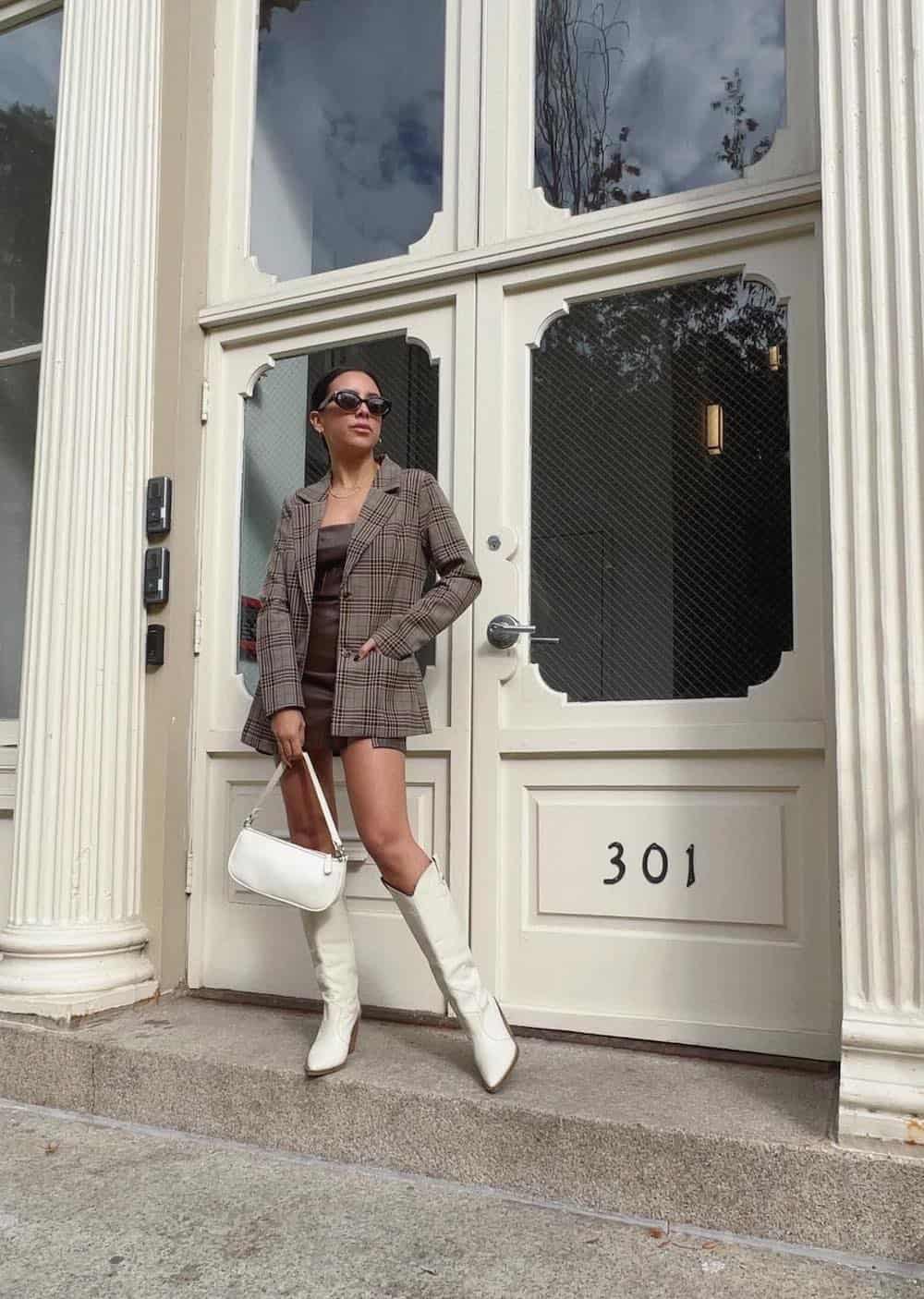 Woman wearing a plaid blazer with white cowboy boots.