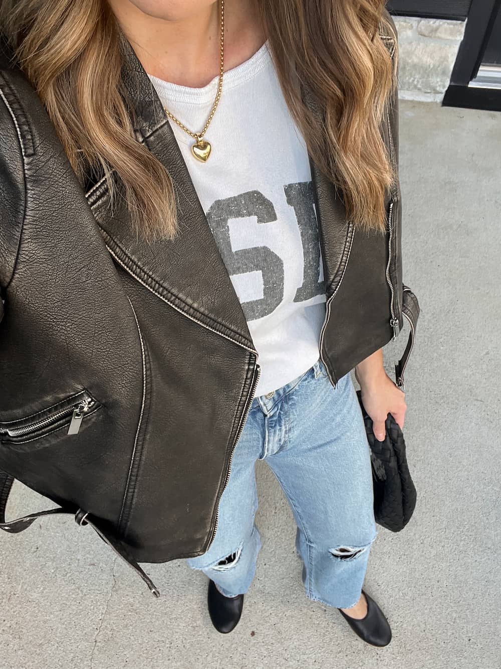close up of a woman wearing a distressed leather jacket, a YSL t-shirt, wide leg jeans, and Mary Jane flats