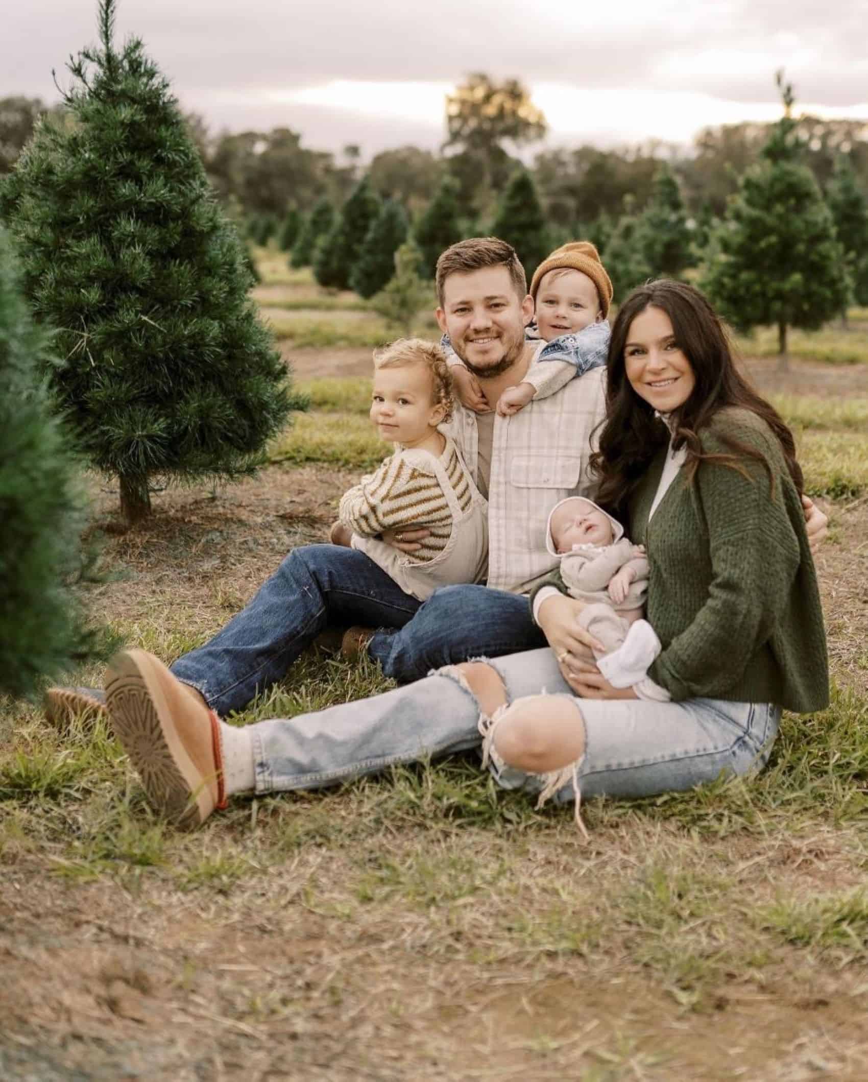 A winter family photo where the the family is dressed casually in jeans, sweaters, and flannels in green, beige, and white tones