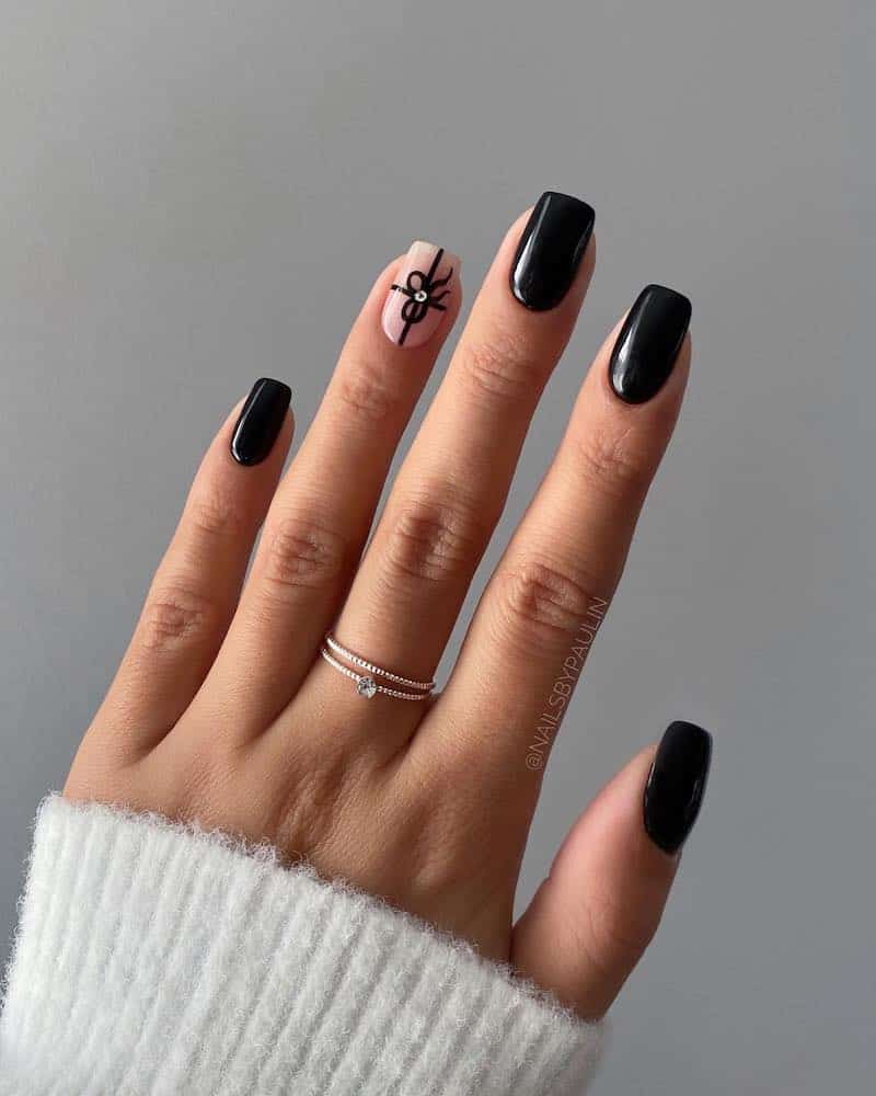 A hand with short black nails and one nude accent nail with a simple Christmas present design