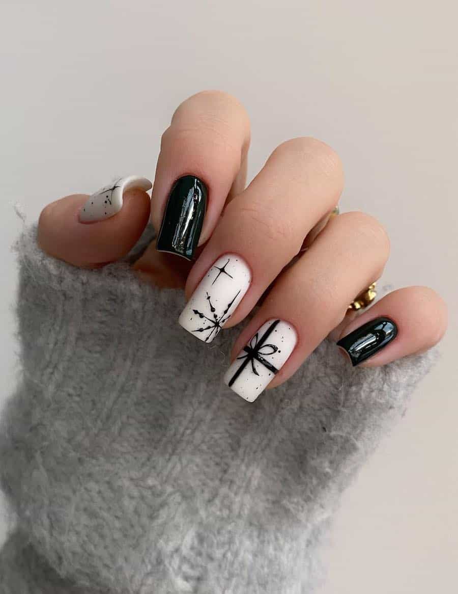A hand with medium-length square nails painted with matte white featuring black present art and snowflake art with two glossy black accent nails