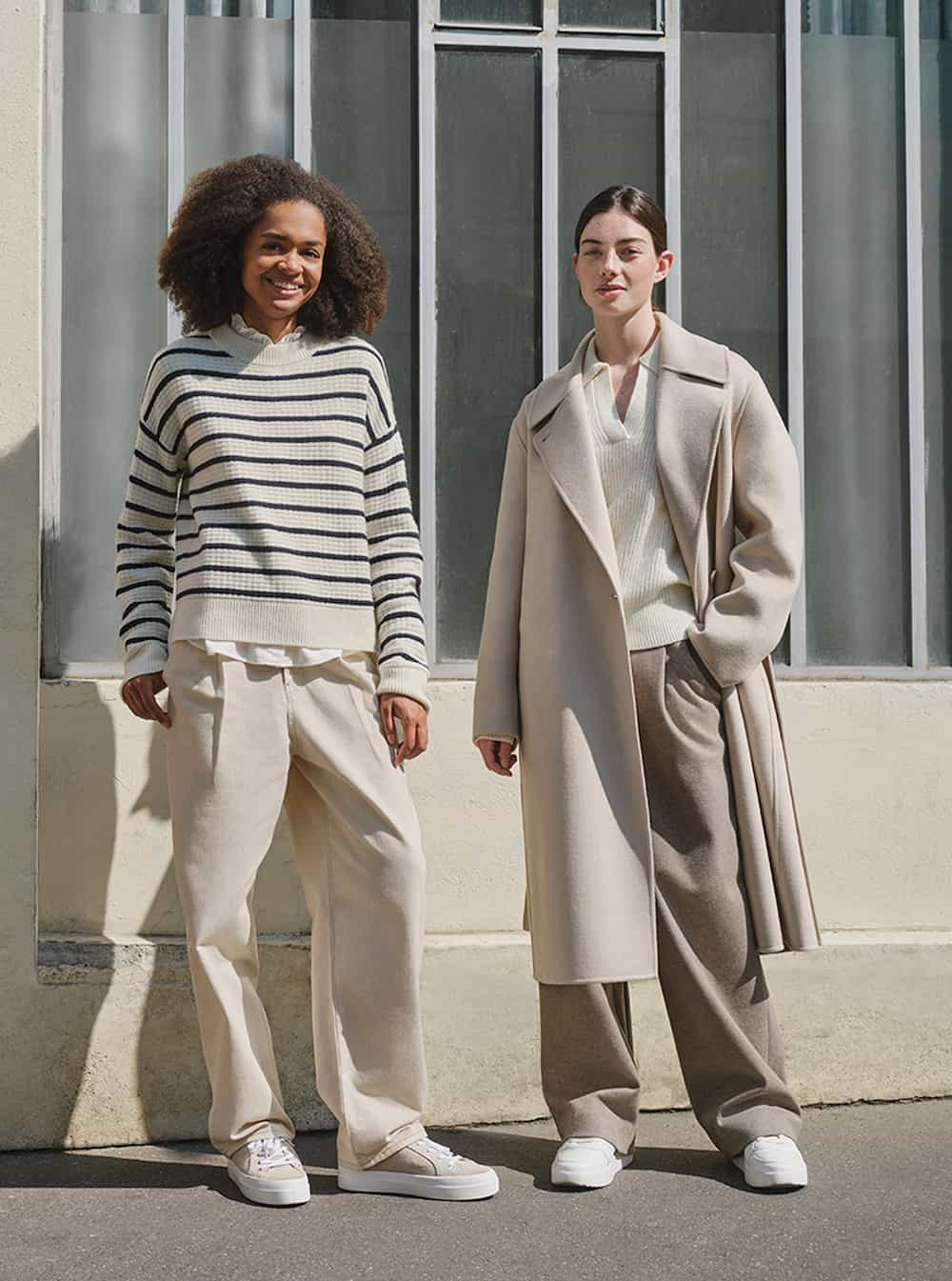 two women wearing neutral outfits with beige trousers, striped sweaters, and beige wool coat from Uniqlo, a store like Everlane