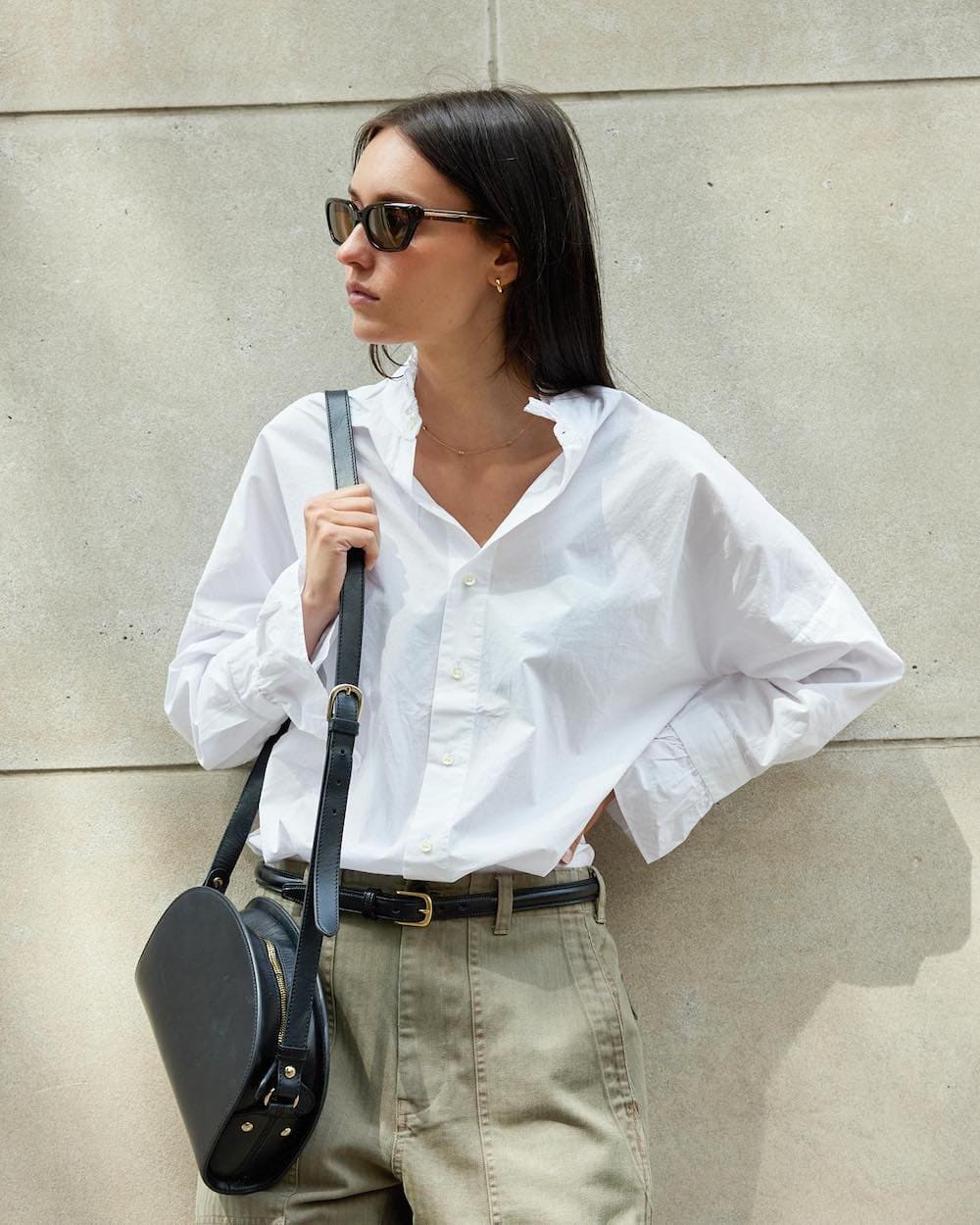 woman wearing a white button-up shirt with green cargo pants and a black belt from Alex Mill, a store like Everlane
