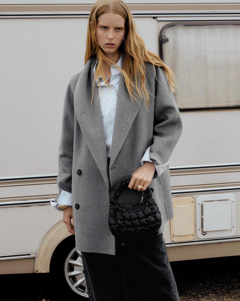 woman wearing a grey wool coat over a striped button-up shirt with black pants from COS