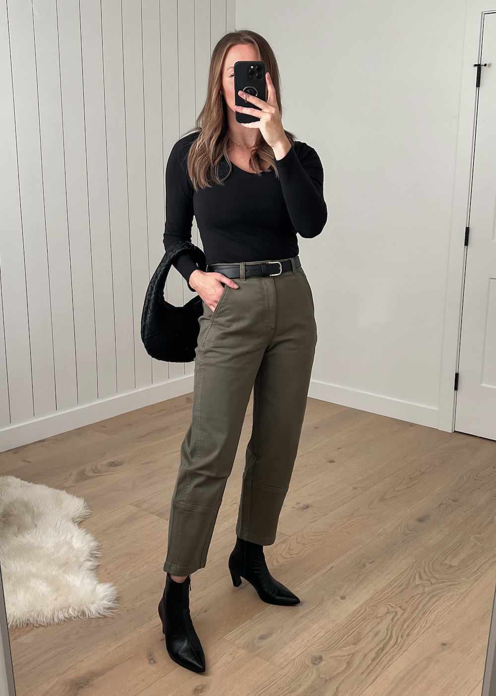 Christal wearing a black long sleeve top with olive green pants and black heeled boots