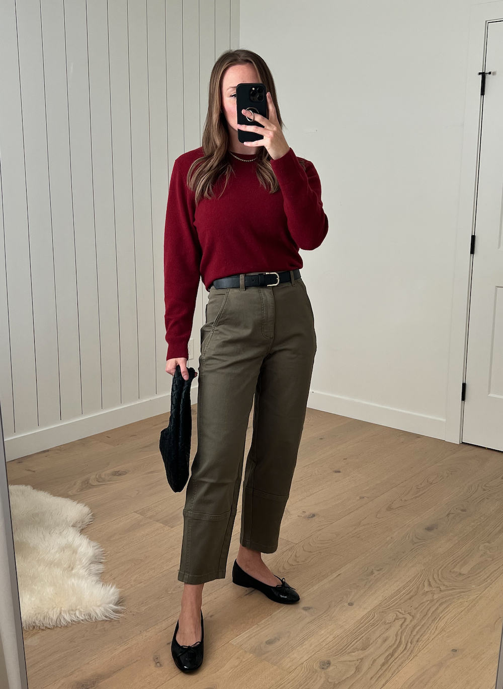Christal wearing a deep red crewneck sweater with a black belt, olive green pants, and black ballet flats