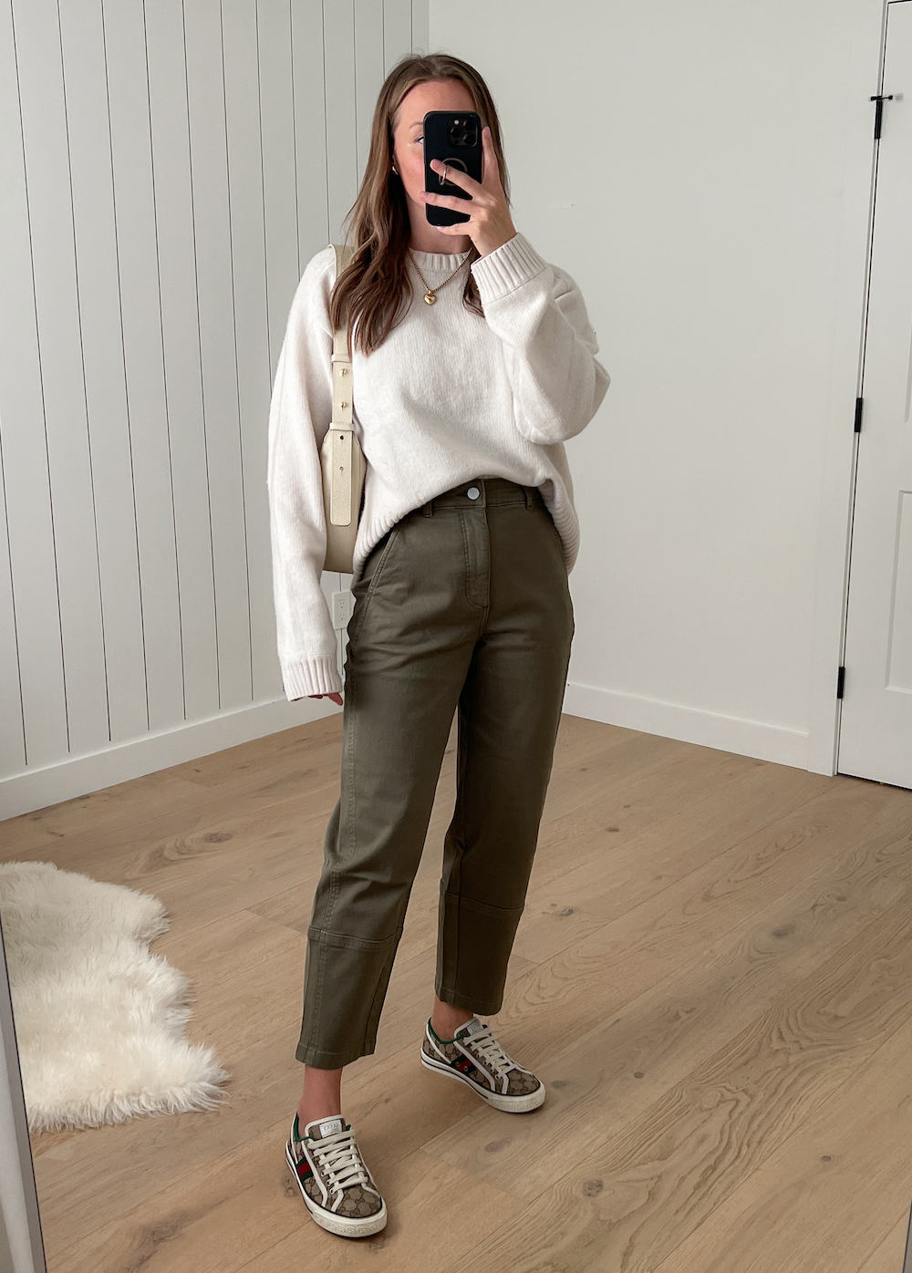 Christal wearing an ivory knit sweater with green barrel pants and tan canvas Gucci sneakers