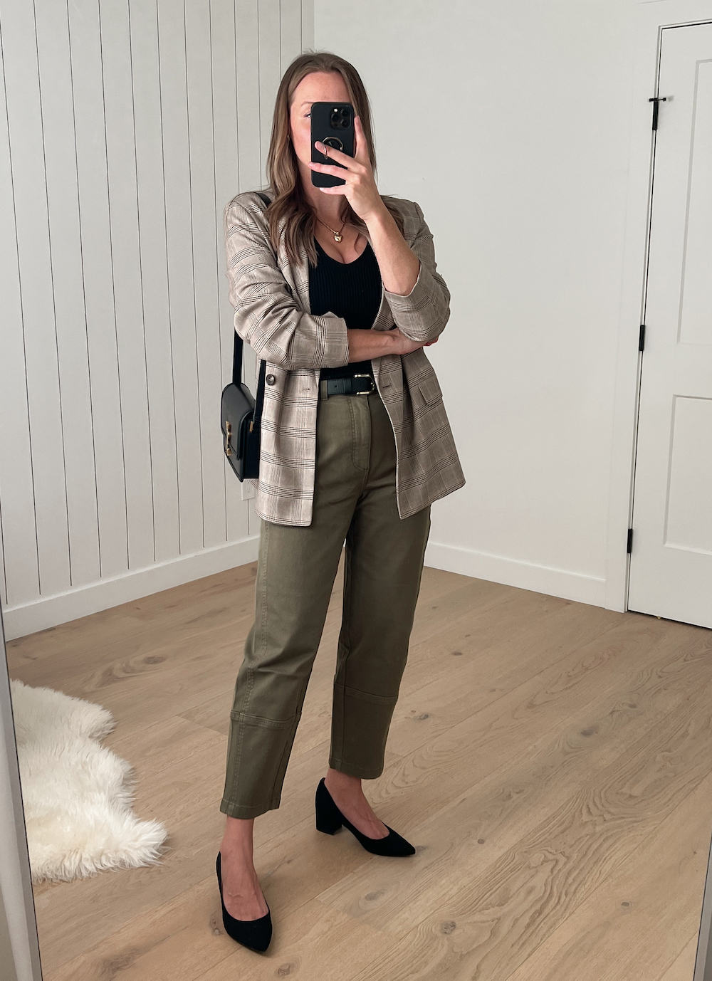 Christal wearing a neutral plaid blazer with olive green pants and black suede heels
