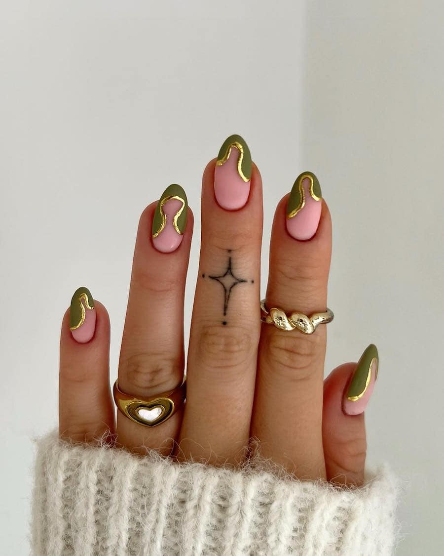 A hand with short pink almond nails with wavy green tips and gold borders