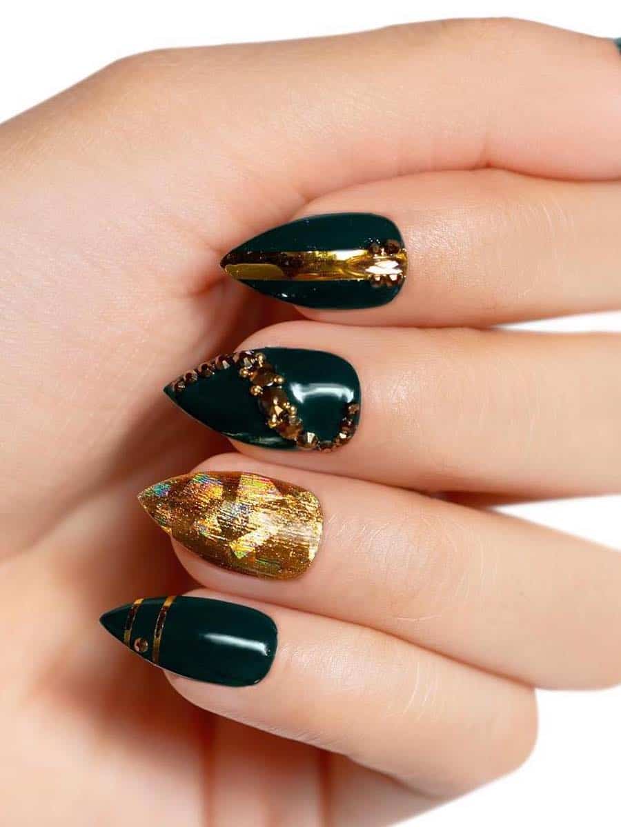 A hand with short stiletto nails painted accent nail, gold bands, and gold beads