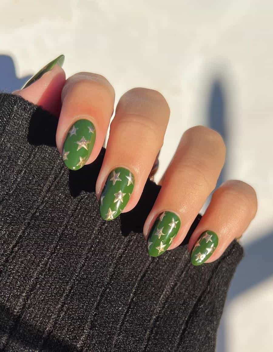 A hand with short green almond nails with gold stars
