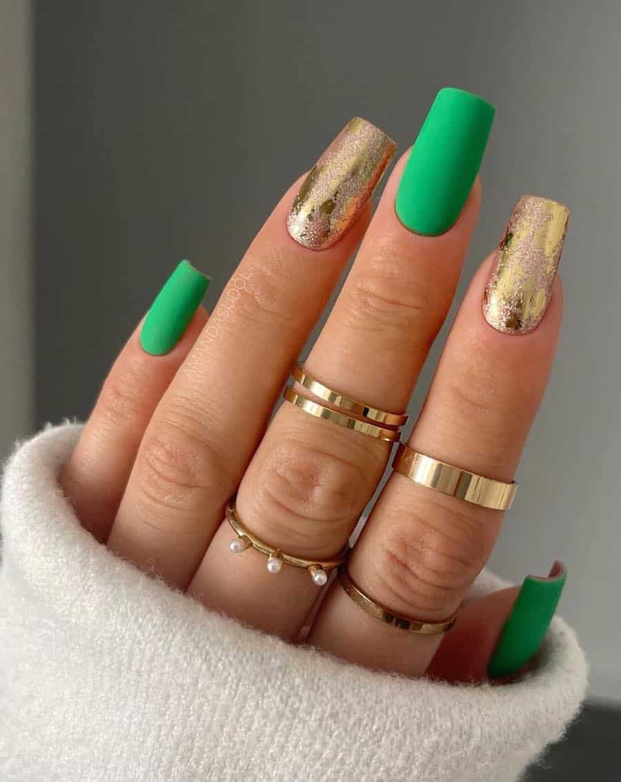 A hand with long square nails painted a matte Kelly green with two distressed gold accent nails