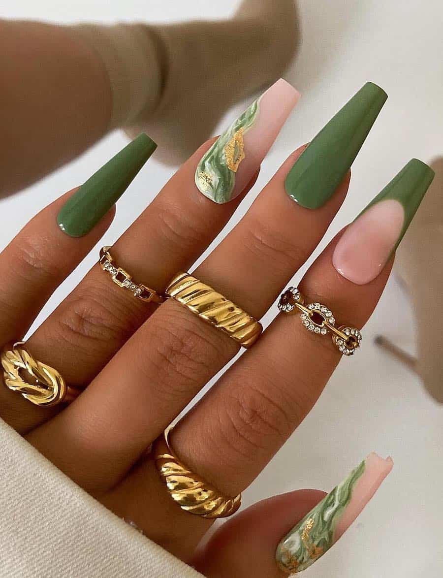 A hand with long coffin nails painted a solid green color with marbled green and white accent nails with gold foil and green French tip accents
