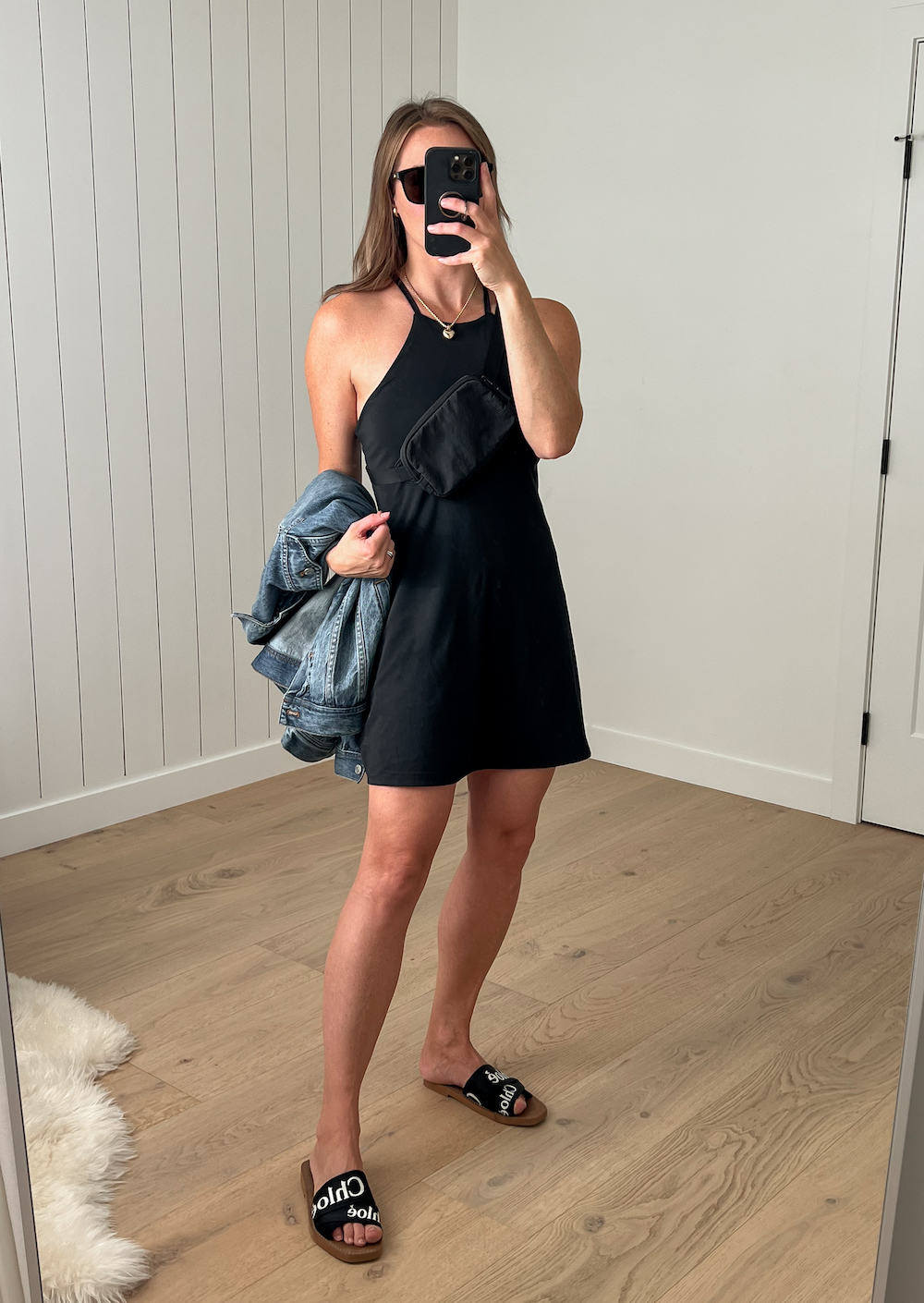 Woman wearing a black dress with black sandals and a Lululemon belt bag.