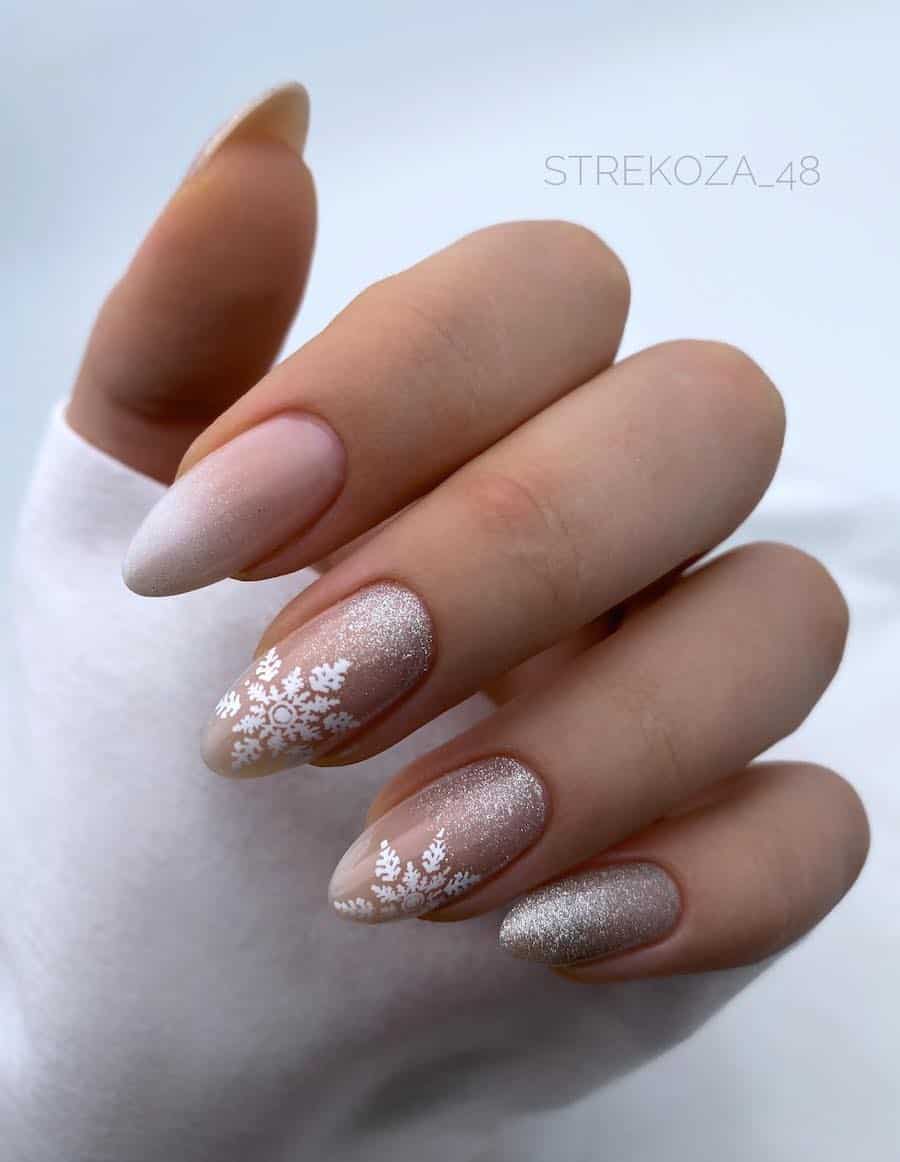 A hand with medium almond nails painted with a clear top coat, featuring silver glitter ombre and white snowflakes with white glitter ombre accent nails and full silver glitter accent nails