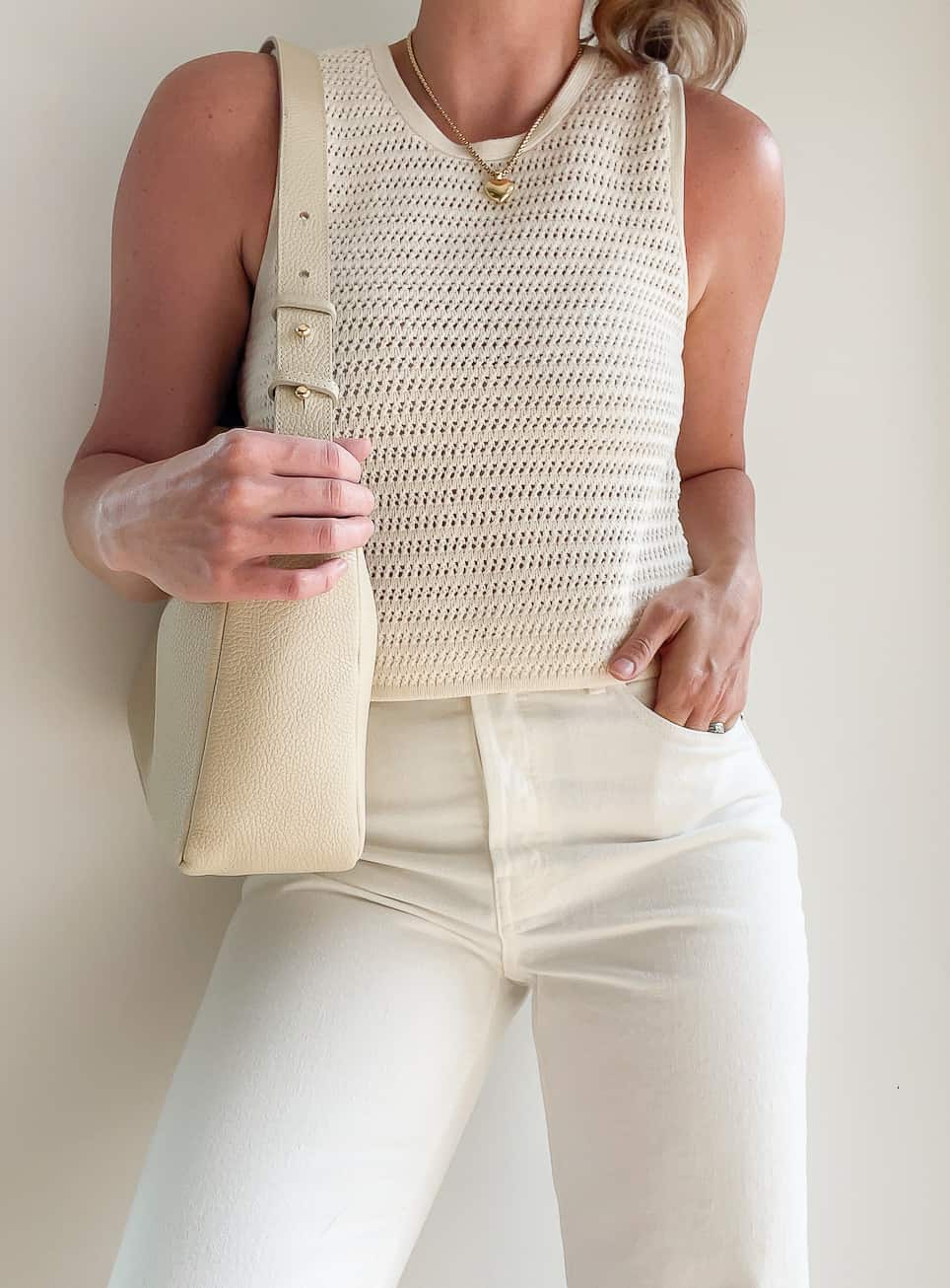 Woman wearing a crochet knit top with white Everlane jeans 