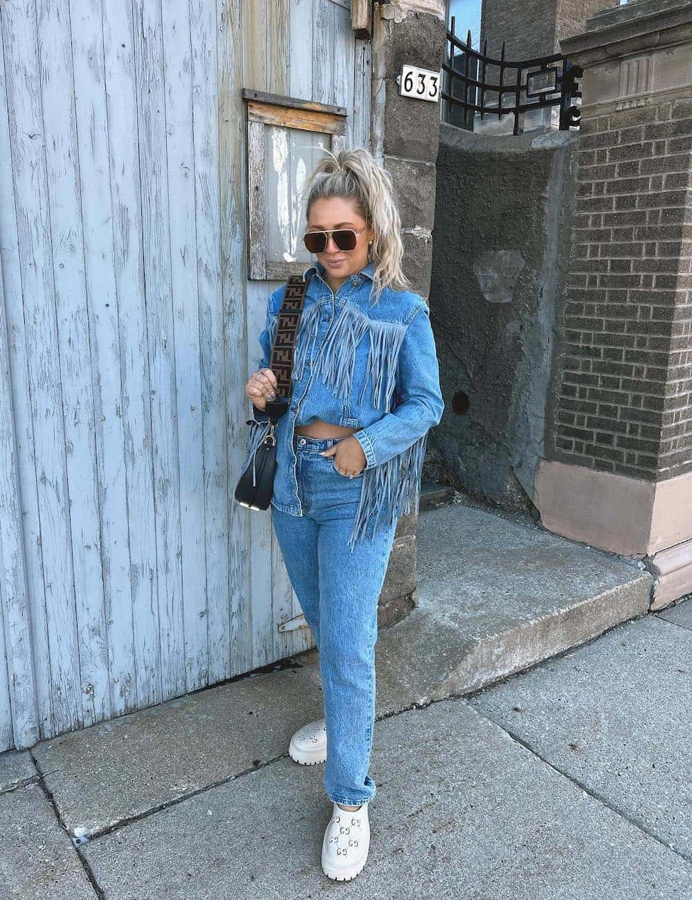 Woman wearing all denim with white clogs.