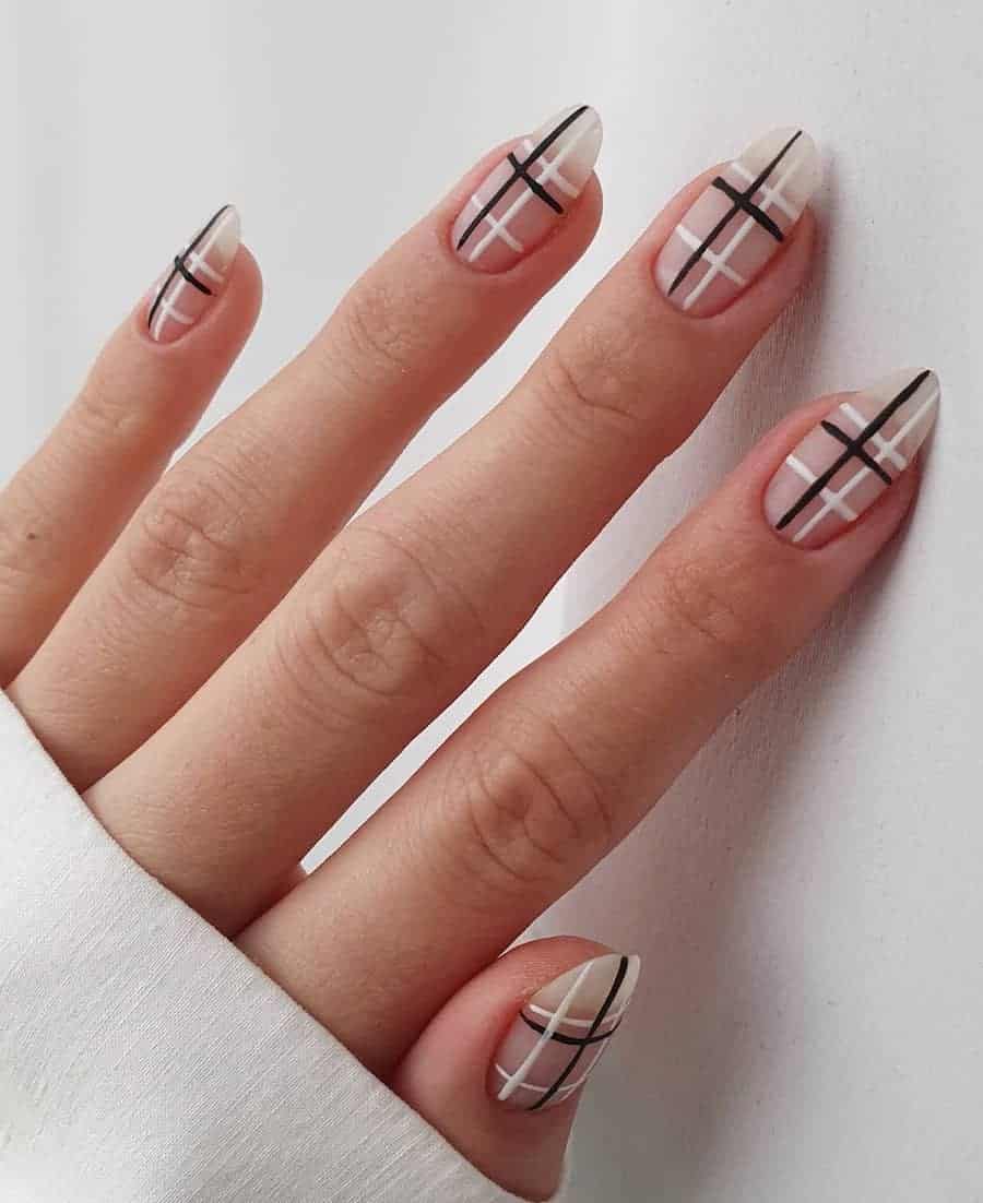 A hand with medium nude almond nails with black and white grid lines