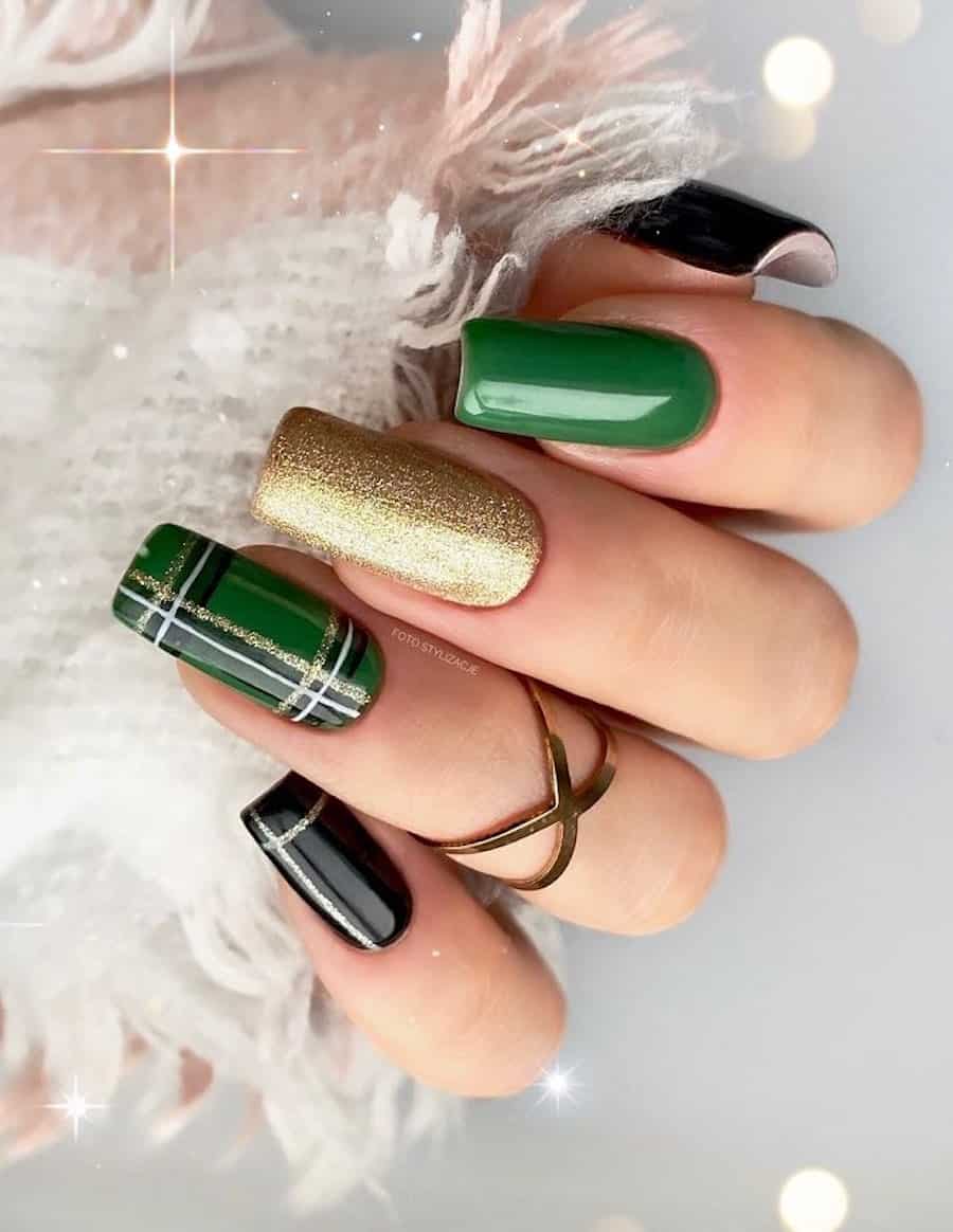 A hand with medium squoval nails painted in shimmering gold, glossy green, and glossy black polish with plaid accent nails