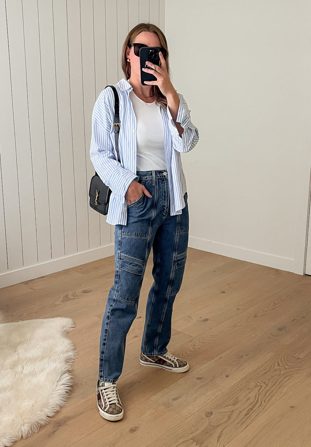 Woman wearing utility jeans, sneakers, a white t-shirt and an oversized button down.