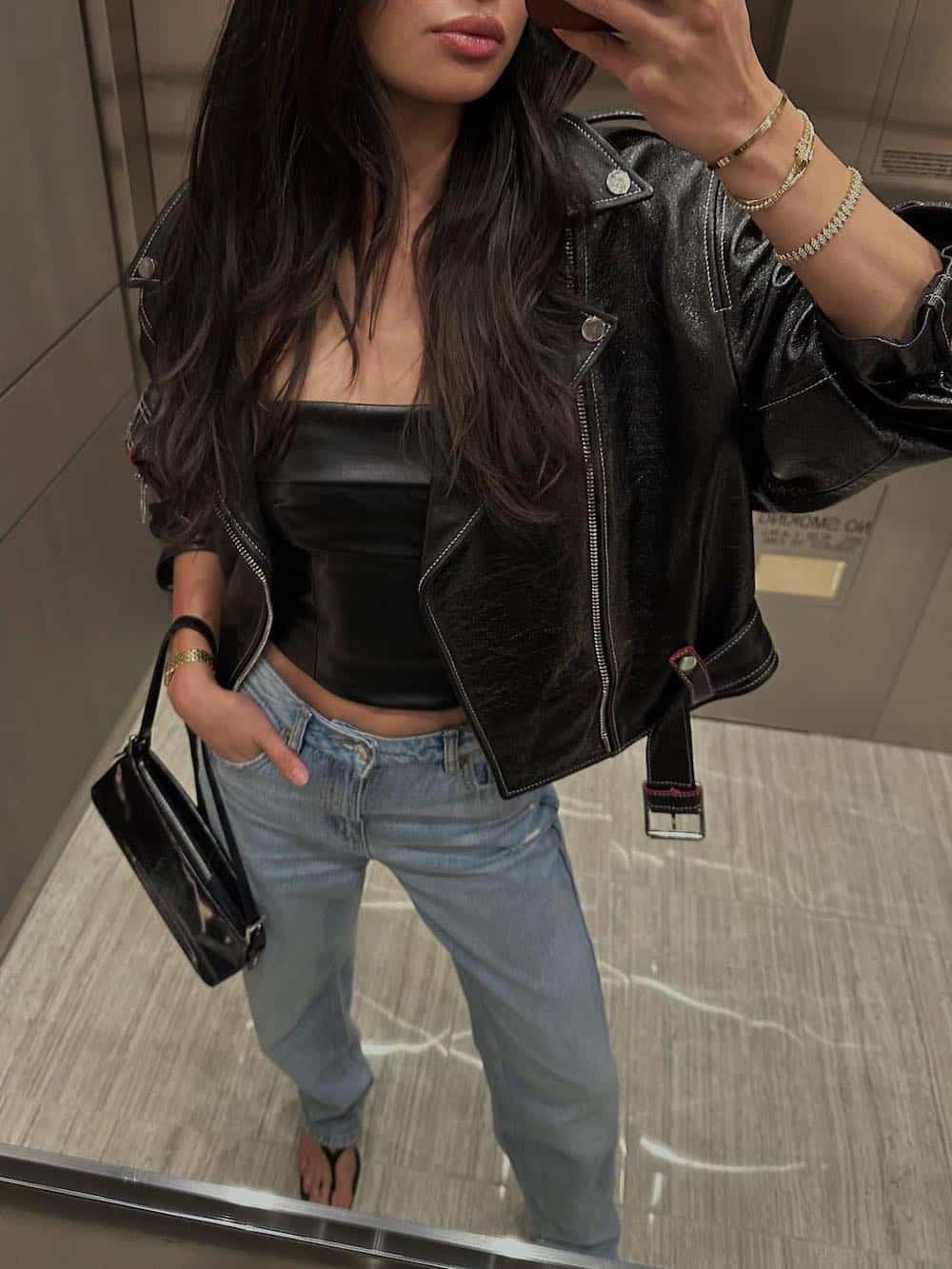 Woman wearing jeans, a black corset top and a black leather jacket.