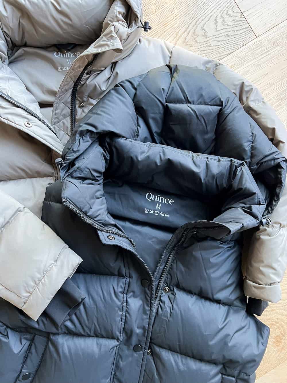 image of a black puffer vest and a taupe puffer jacket flatlay 