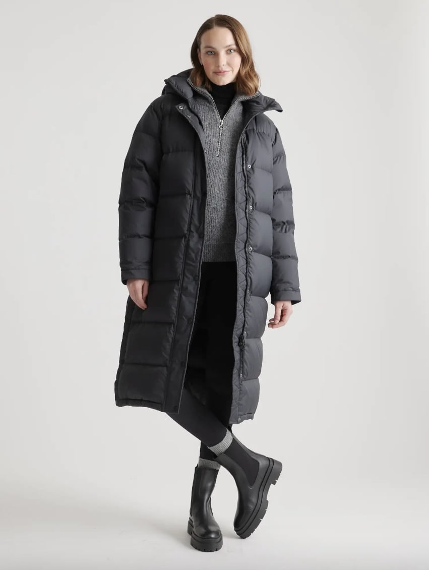 woman wearing a long black puffer coat that's an Aritzia superpuff dupe with a grey sweater, black pants, and black boots