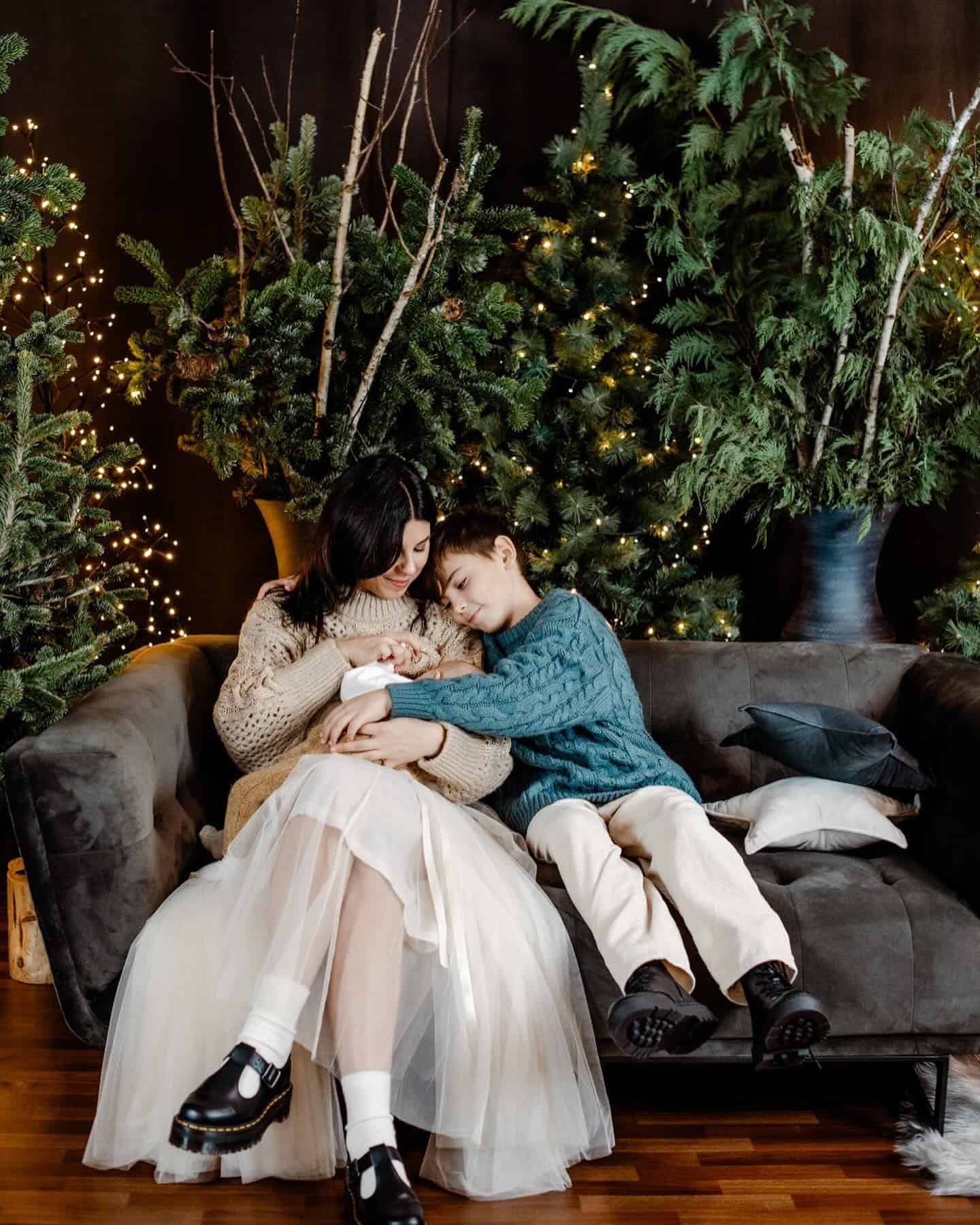 A Christmas family photoshoot with a mother and her children, wearing a white tulle skirt, white pants, and cable knit sweaters