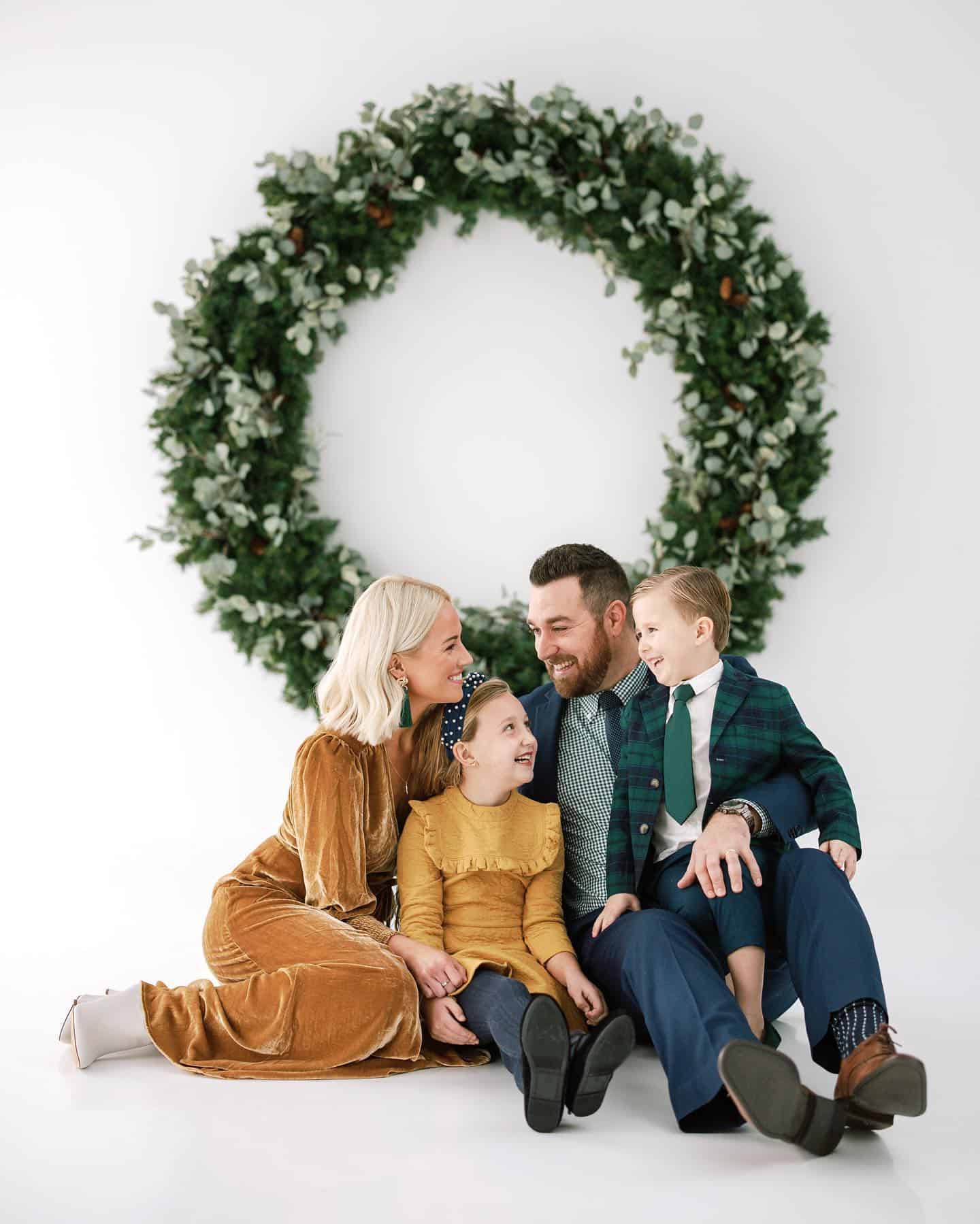 A family photoshoot with a family of four wearing shades of mustard, navy, and emerald green