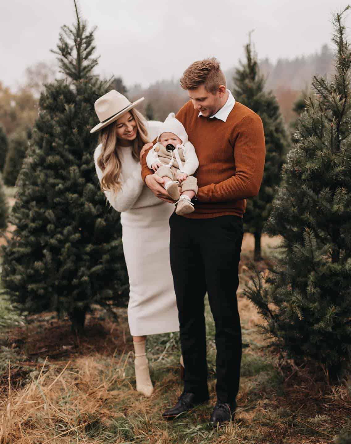 A Christmas family photoshoot with a family of three wearing knit pieces in brown, white, and black
