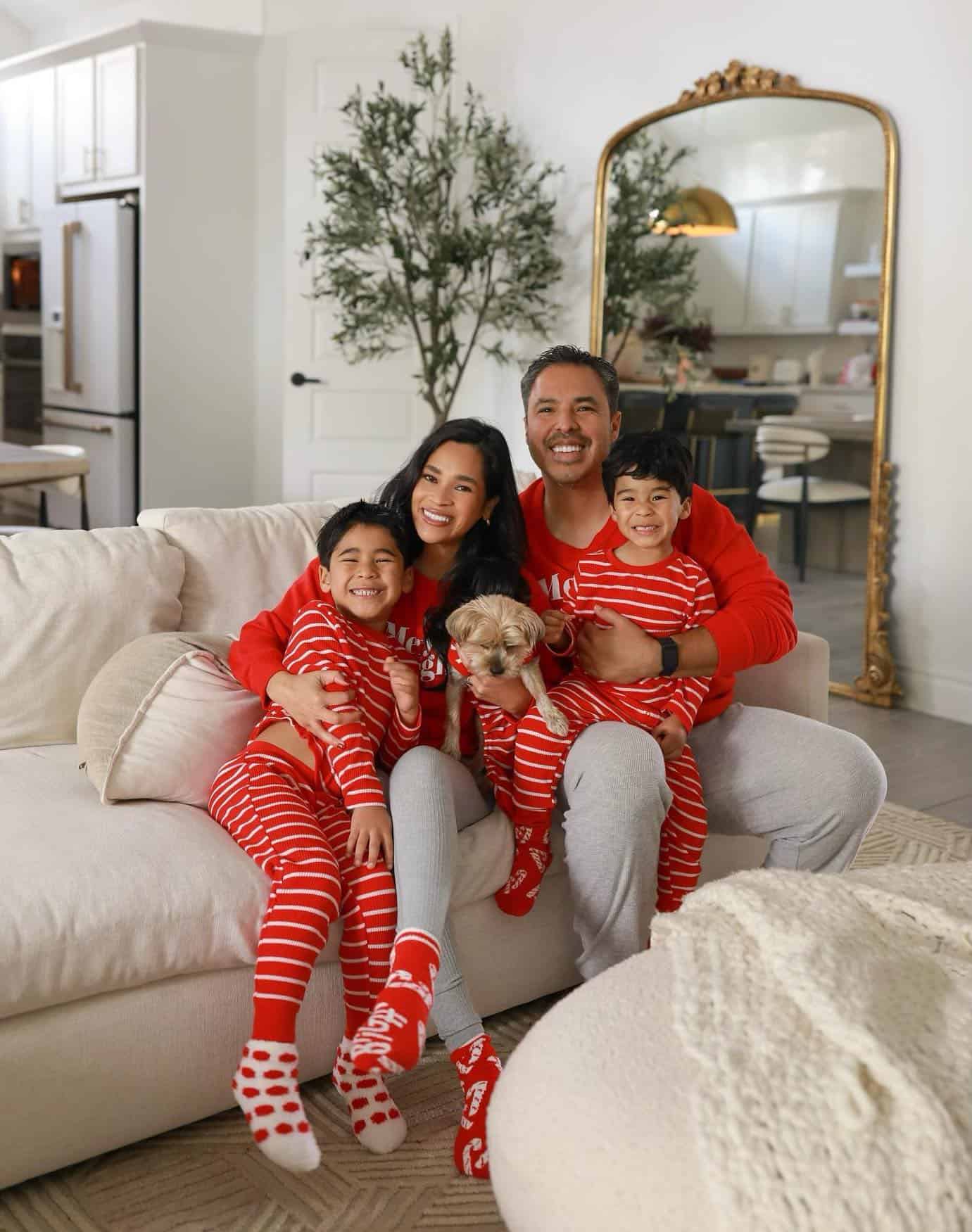 A family photo with a family of four and their dog wearing matching red, white, and grey Christmas pajamas