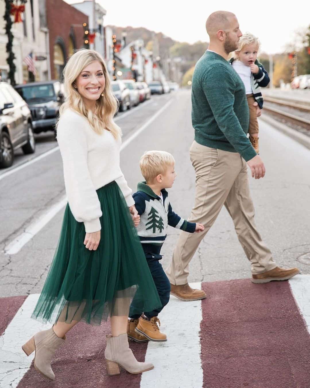 A family winter photo with a family of four wearing white, beige, and green pieces