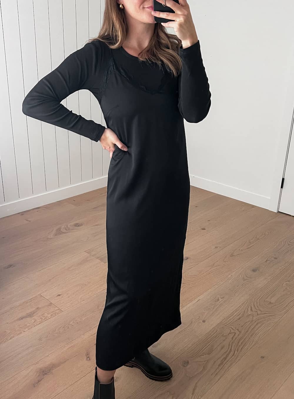 Christal wearing a black slip dress with a long sleeve tee under and black Chelsea boots.