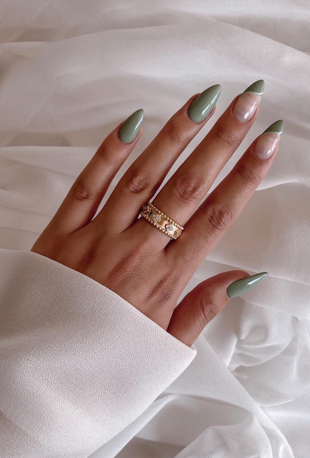 and image of a hand with sage green nail polish, natural nail spaces, and white line designs