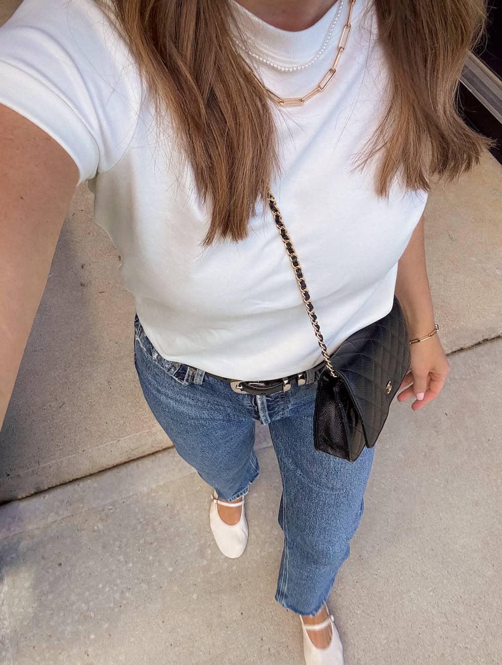 women wearing a white t-shirt with blue straight-leg jeans and cream Mary-Jane flats