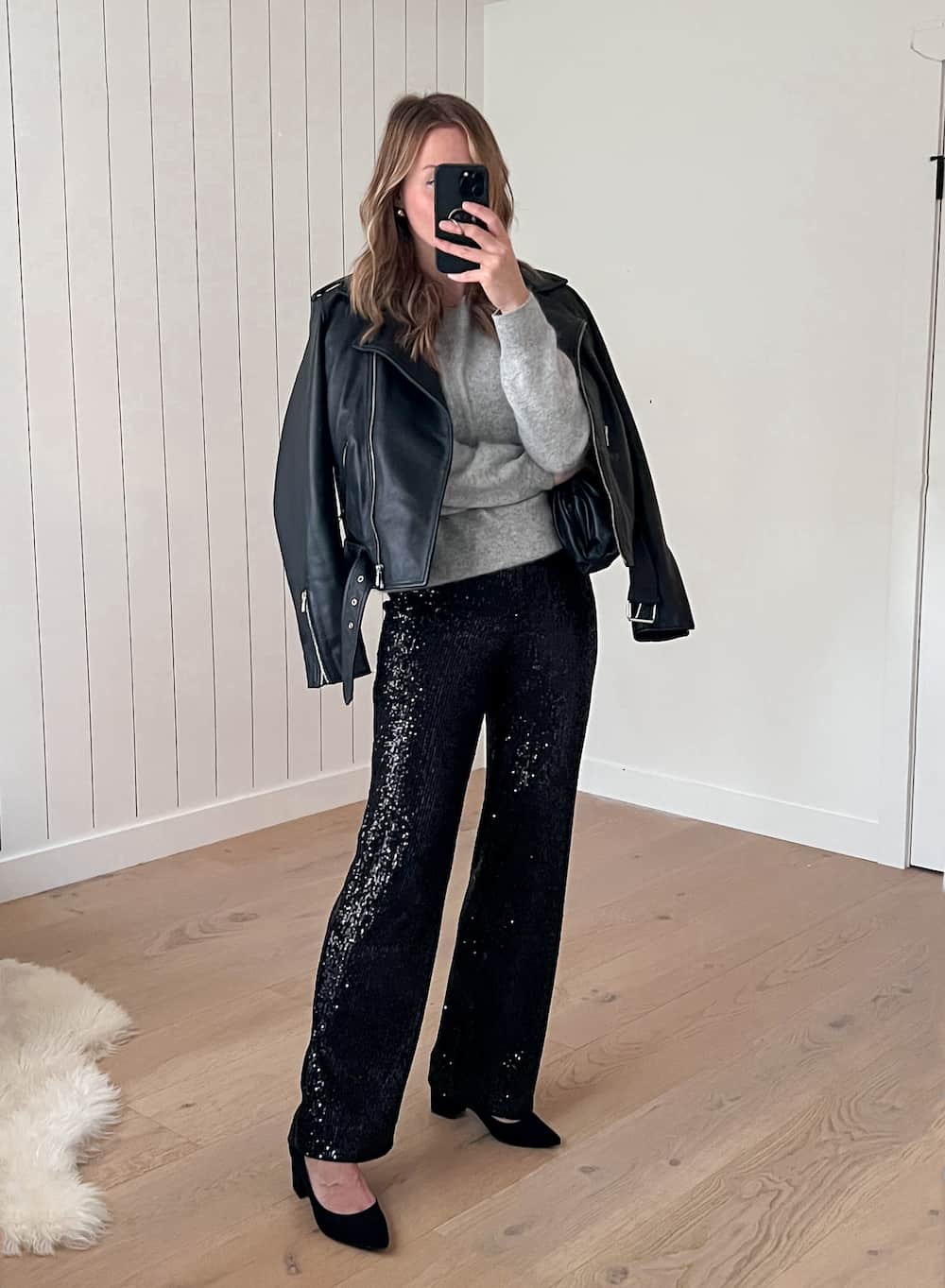 Christal wearing sequin pants, a grey sweater, a black leather jacket and black pumps.