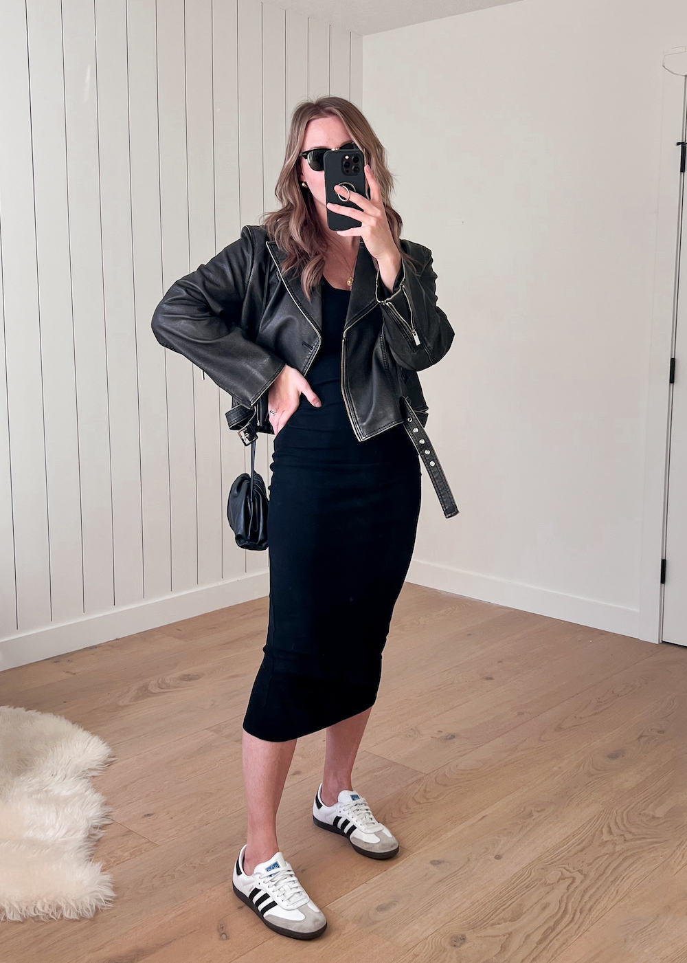 Christal wearing a knit midi dress with a black leather jacket and sneakers.