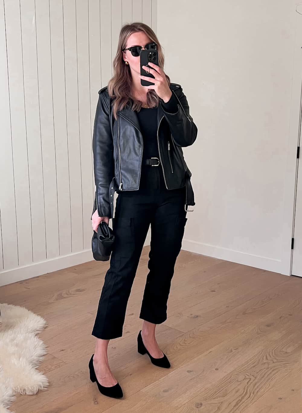 Christal wearing black jeans and a black knit top with a leather jacket and pumps.